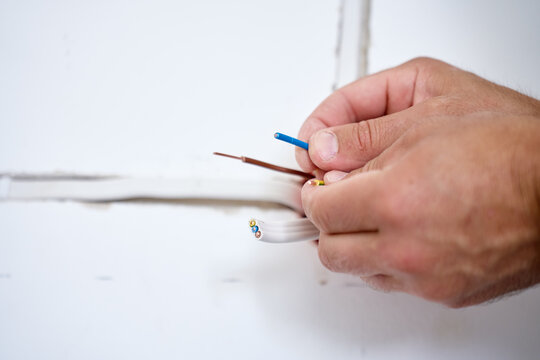Hands holding stripped electrical wires and cable for wiring installation