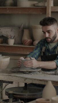 Slow motion portrait of skilled man in apron manufacturing ceramic pot in workplace. Creative guy enjoying traditional occupation developing small business.