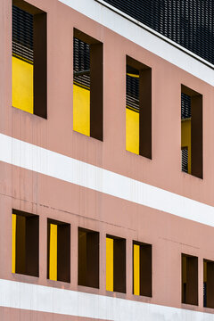 Modern residential facade with yellow windows creates an apartment pattern where urban architecture repeats through geometric openings across the building