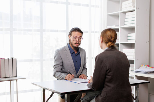 Job interview candidate communicating with a recruiter, discussing employment opportunities, career development, and signing application documents in a professional office setting