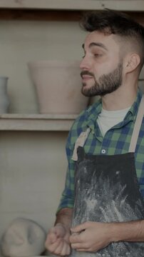 Young man in dirty apron talking to female colleague discussing pottery business and looking at pots. Creative entrepreneurs and conversation concept.