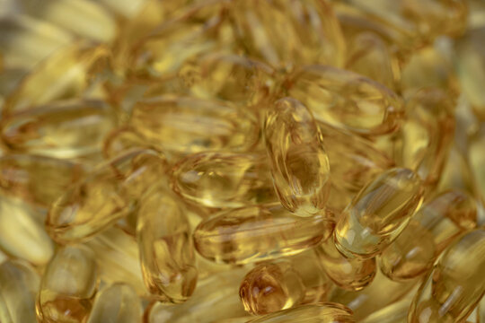 Macro close-up of transparent Omega-3 fish oil capsules. Golden softgel supplements for health, wellness, nutrition and dietary supplement concepts.