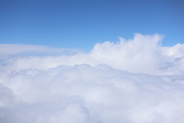 Obraz premium Aerial view of fluffy white clouds and bright blue sky background 