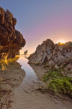 Low tide at Playa de Buelna Beach during a spectacular, fiery dawn with a rock-framed view of 'El Pic&oacute;n' limestone pinnacle. Llanes-Asturias-Spain-083