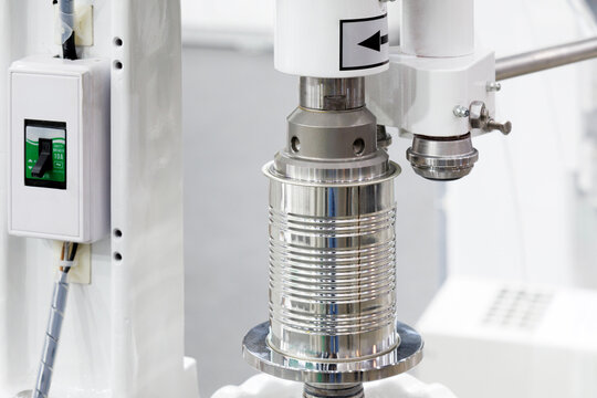 automatic can seaming machine seals metal tin can in modern packaging and food processing factory. aluminum cans processed on conveyor belt machine in canned food manufacturing. industrial technology