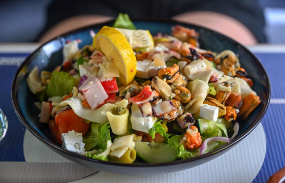 Fresh seafood salad served in a restaurant with shrimp, mussels, squid, cuttlefish, and octopus. Delicious gourmet seafood salad featuring mixed marine delicacies on a plate.