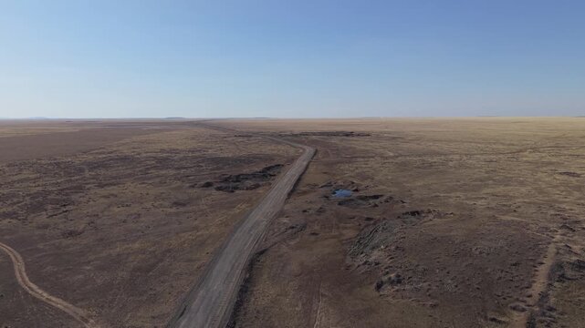 Aerial view of the vast arid landscape of the Semipalatinsk Nuclear Test Site with a dirt road stretching across the steppe in Semey, Abai Region, Kazakhstan.