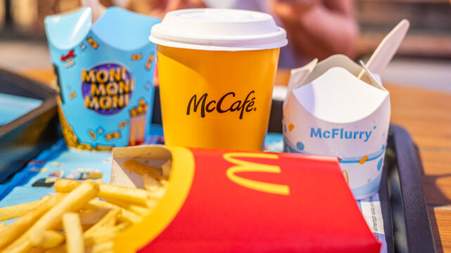 McDonalds French Fries, McCoffee in Yellow Takeaway Cup and McFlurry on Tray and person in the background
