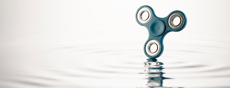 Fidget spinner creating ripples on calm water surface, symbolizing zen and focus
