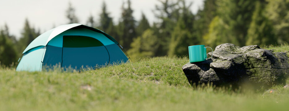 Turquoise camping tent set up on a grassy hill with a mug on a rock