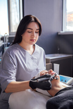 Female aesthetician performing facial treatment on client in modern beauty salon, showcasing advanced skincare techniques and professional equipment for rejuvenation