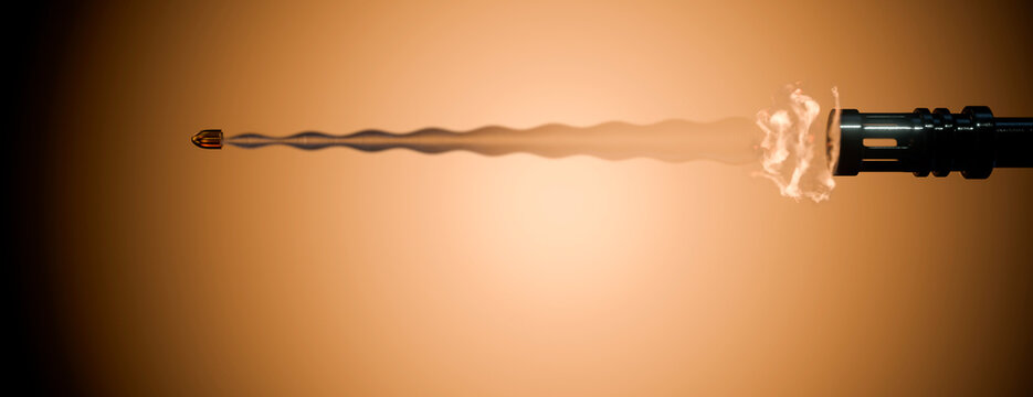 Bullet exiting a firearm barrel with muzzle flash and smoke trail