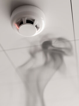 Smoke detector alarm activated by rising smoke on a white ceiling