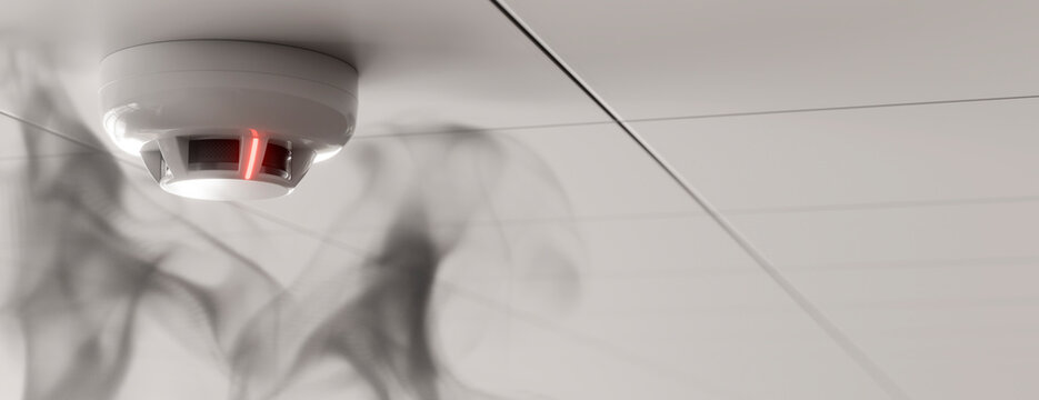 Smoke detector with red light indicating an alarm on a white ceiling