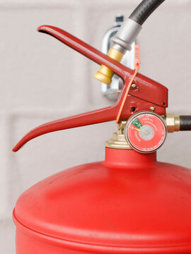 Close-up of a red fire extinguisher with a pressure gauge and safety seal