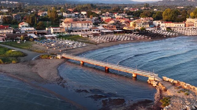 Scenic aerial view of Roda beach resort showing a wooden bridge pier over the sea and sandy coastline in North Corfu, Greece
