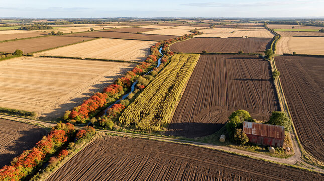 Aerial view of autumn farmland with river and old barn in countryside landscape