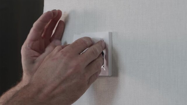 Electrician snapping on light switch cover and testing toggle button response