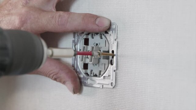 Tightening electrical socket mechanism into wall box using cordless power tool