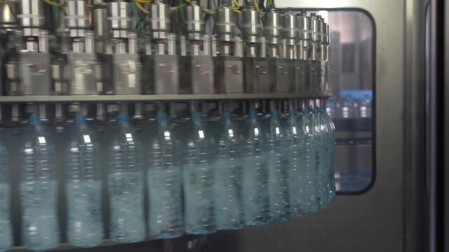 Plastic Water Bottles Moving Through Automated Filling Machine