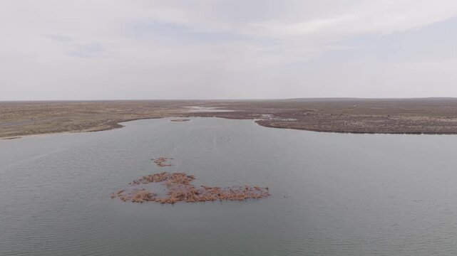 Aerial view of a small houseboat floating on the calm waters of the Aral Sea near the arid coastline of Aral'sk, Aral, Kyzylorda Region, Kazakhstan.