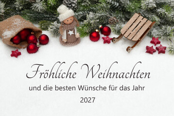 Fototapeta premium Glückwunschkarte zu Weihnachten und Neujahr 2027 mit Weihnachtskugeln, Holzschlitten und Weihnachtspuppe im Schnee.