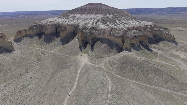 Aerial view of the unique Sherkala mountain with its distinctive dome shape and steep cliffs rising from the arid desert landscape of Aktau, Mangystau Region, Kazakhstan.