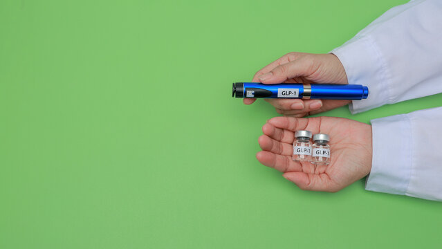 Doctor hand holding glp1 injection pen beside medicine vial with careful hopeful feeling for diabetes treatment on green background