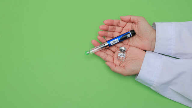 Doctor hand carefully holds glp1 injection pen and medical vial with caring emotion for diabetes treatment on green background