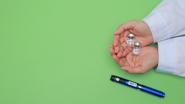 Careful doctor hands holding medical vial bottle beside glp1 injection pen for diabetes and weight loss therapy on green surface