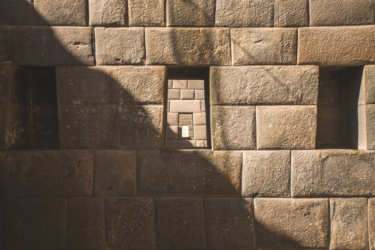 View of the intricate Inca stone masonry wall featuring perfectly fitted blocks and a trapezoidal window in Cusco, Cusco, Peru.