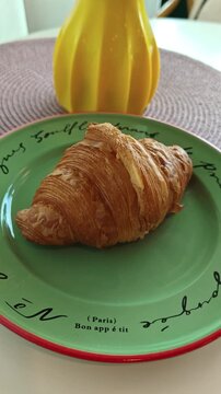 croissant on plateFreshly baked French croissant on green ceramic plate, panning shot, bakery and cafe concept.