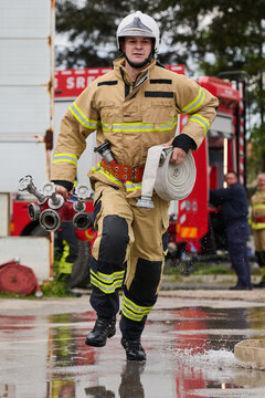 Firefighter Running With Hose And Valve Equipment Carrying Out Emergency Response Near Fire Truck