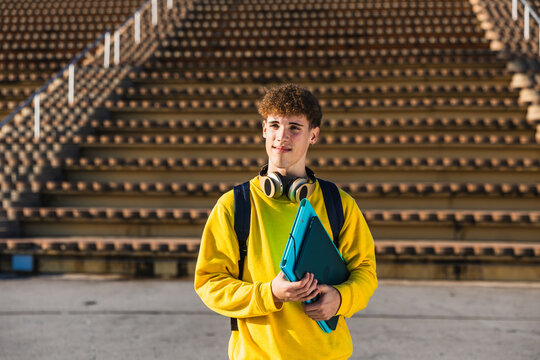 College student holding books and looking away in university campus