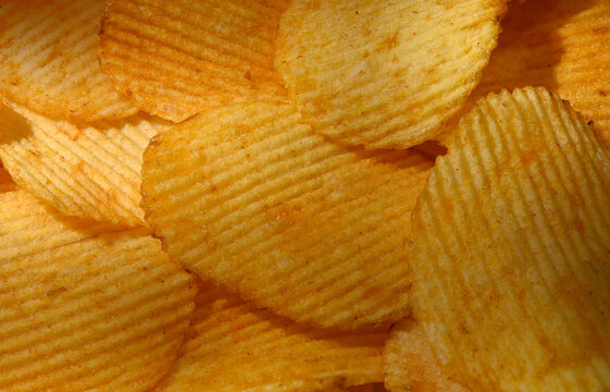 Commercial food photography of a macro background of crispy ridged potato chips with golden texture