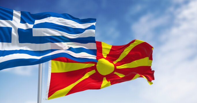 Flags of Greece and North Macedonia waving in the wind on a clear day