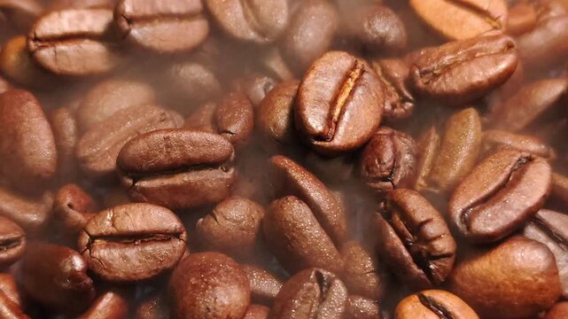 Macro Shot of Steaming Coffee Beans Stock Video. High-definition macro video footage of roasted coffee beans with dense steam wafting across the frame, ideal for culinary and beverage projects.