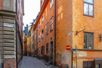 Fototapeta premium The historic Storkyrokobrinken and Prästgatan street intersection with vibrant orange facades in the medieval Gamla Stan old town of Stockholm, Sweden.