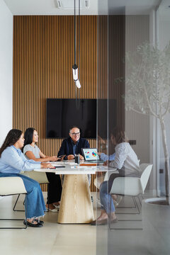 Multiracial colleagues working inside business office with glass walls - Brainstorming concept - Main focus on center man face - Vertical photo - UGC photo
