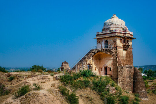 View of the historic Raja Maan Singh Haveli featuring a stone dome and an external staircase set against a clear blue sky in Jhelum, Punjab, Pakistan.