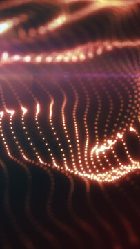 Abstract orange particle waves curve through a dark tunnel, creating a luminous flowing pattern with selective focus.