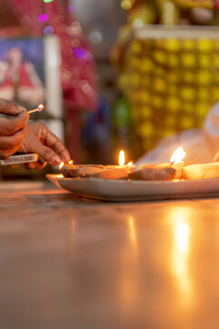 View of a person lighting traditional clay oil lamps for the Diwali festival with warm glowing flames in Rahim Yar Khan, Punjab, Pakistan.