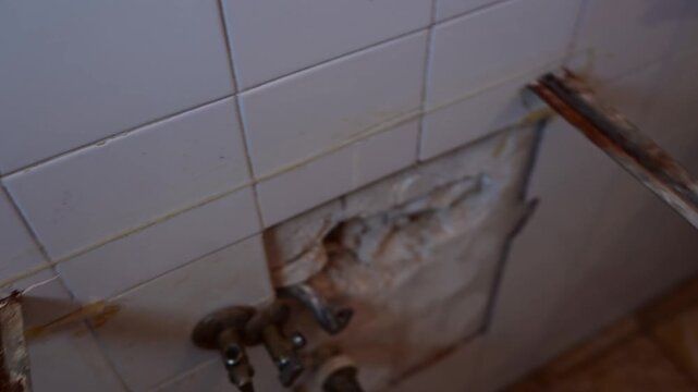 Plumber carrying away broken toilet cistern during bathroom renovation