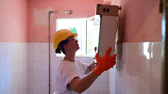 Female construction worker demolishing a bathroom cabinet
