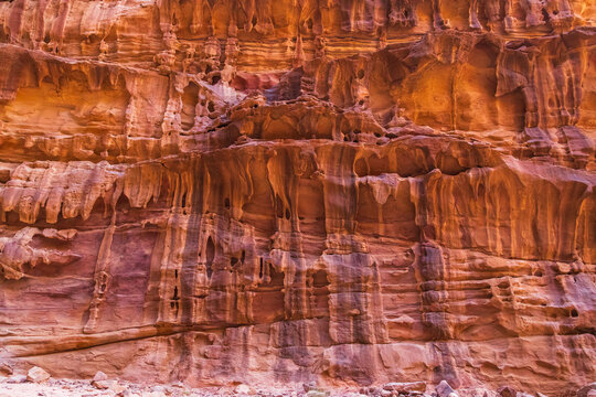 View of Wadi Rum Protected Area featuring towering red sandstone cliffs with intricate erosion patterns and warm desert light in Wadi Rum Village, Aqaba Governorate, Jordan.