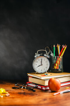 Back to School Supplies on Wooden Desk with Alarm Clock, Apple and Colored Pencils