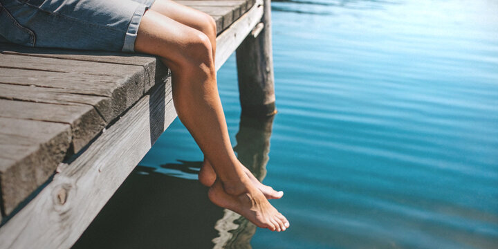 Summer holidays and peaceful relaxation of working adults with people sitting on the wooden pier by the river
