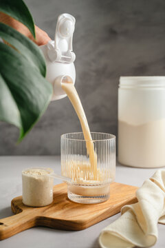 Pouring protein shake into glass, post workout nutrition and healthy lifestyle concept