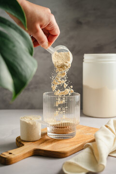 Preparing protein shake with whey powder supplement and empty glass