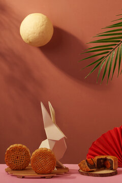 Mid-Autumn Festival composition with mooncakes origami rabbit and moon on terracotta background